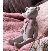 Vintage stílusú, enyhén kopott, antik krém színű, ülő helyzetű nosztalgikus maci figura, púderrózsaszín színű masnival a nyakában